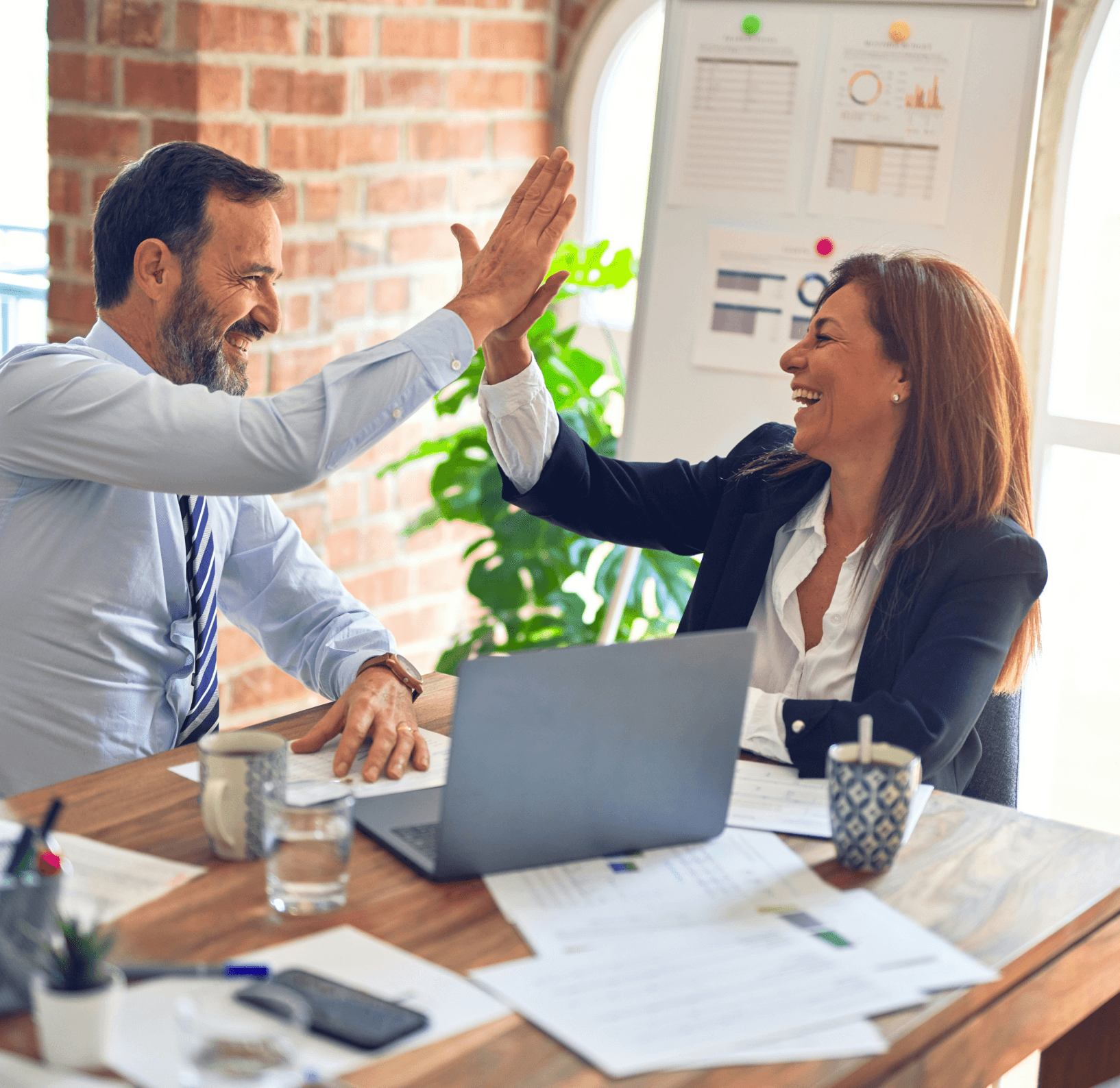 A man and woman coworker high-fiving each other in celebration