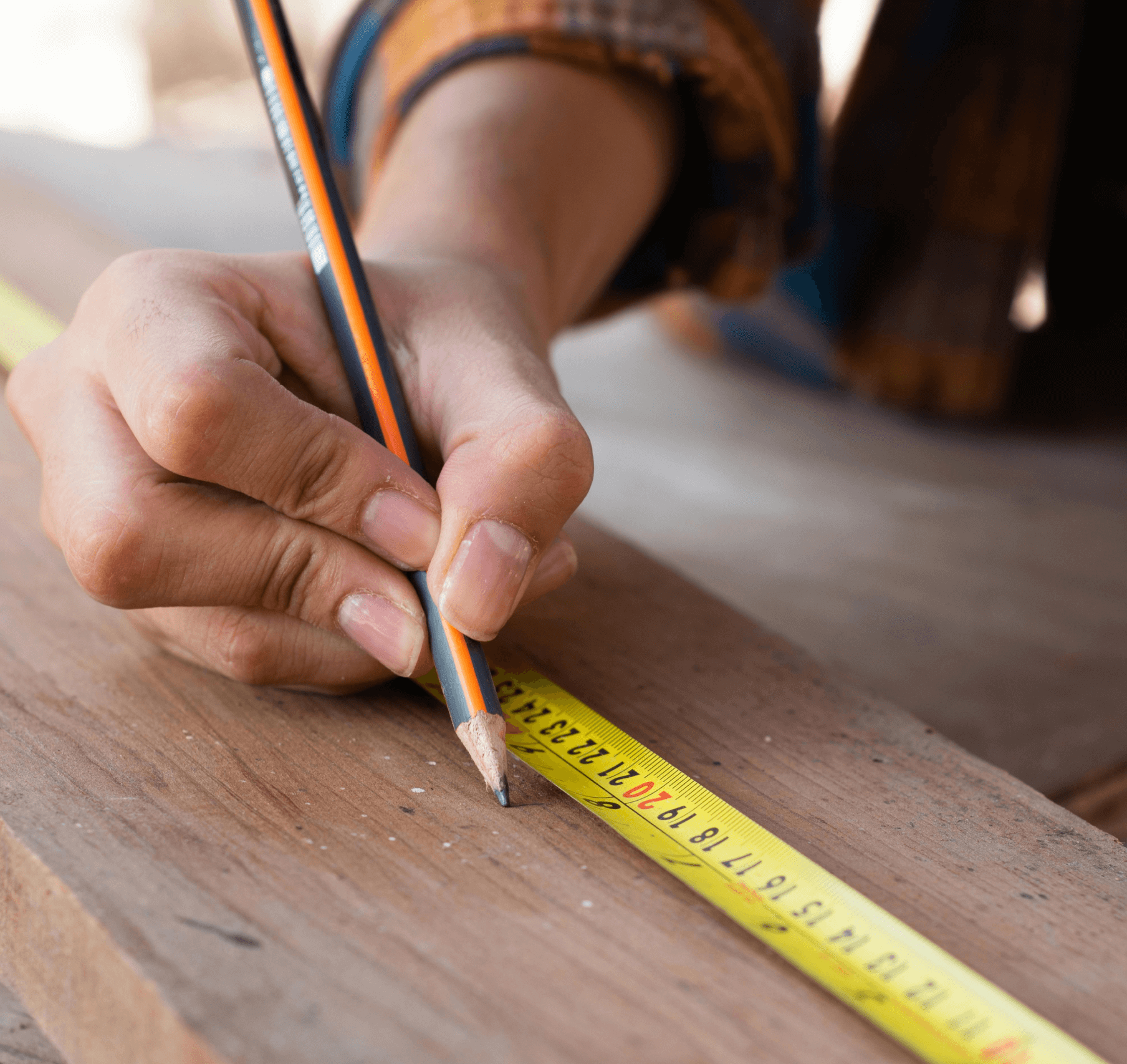 Person using a measuring tape on a piece of wood